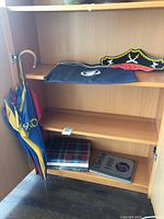 Open cabinet showing umbrella, plaid book, silver 1988 yearbook