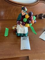 Front view of Royal Doulton figurine showing elderly woman with balloons and basket
