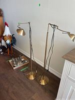 Two brass-finish floor lamps standing side by side