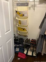 Full view of closet area showing hanging organizer, shoe rack, shoes, bags