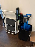 Stool folded with shovels and brushes in bin