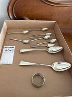 Box view showing nine spoons and napkin ring