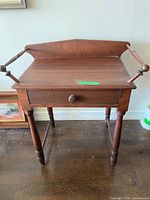 Front view of wooden washstand showing drawer, legs, towel bars