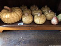 Front view of complete set showing large tureen, eight lidded bowls, pear accent