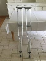 Full view of both aluminum crutches standing upright on floor