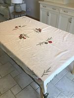 Full view of tablecloth on dining table showing cream color and holiday motifs
