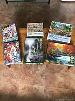 All six puzzle boxes on table showing range of piece counts and images