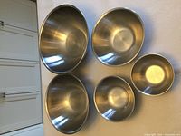 All five nesting stainless steel bowls displayed on wall to show size range