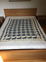 Blanket spread on bed showing full design, plaid center, loon border and fringe