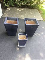 Three blue square planters and saucer shown together outdoors