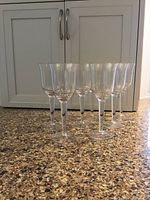 All eight clear plastic wine glasses grouped together in front of cabinet