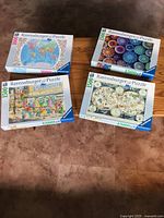 Group shot of four Ravensburger puzzle boxes showing titles and piece counts