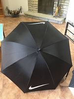 Full view of black Nike umbrella canopy displaying two white swoosh logos
