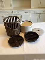 All components disassembled: wicker outer basket, fabric drum insert, two plastic trays, fabric lid