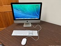 Front view of iMac displaying macOS Mavericks with keyboard and mouse