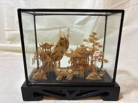 Front view of the wood diorama inside glass case on black base