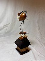 Front view of entire wood bird sculpture showing all three birds and house base