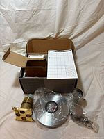 All kit components laid out with box, instructions, valve body, trim plate, handle, sleeve