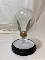 Front view of Golden Snitch under clear dome