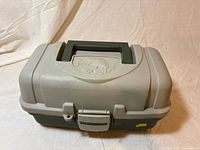 Closed tackle box front view showing latch, handle, fish motif on lid