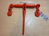 Top view of orange ratchet binder with ruler for scale, hang tag visible