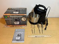 Mixer assembled on stand with bowl, accessories laid out, box and manual visible