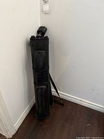 Closed black cue case leaning in corner