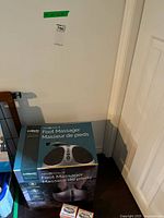 Boxed truMedic foot massager beside wall with foot care boxes