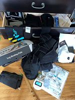 Drawer and floor showing multiple medical and therapy devices including boxed leg heating pads, Resperate device, electrotherapy unit, braces, socks, foot roller