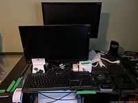 Two monitors, keyboards, router, power strip and cords on desk
