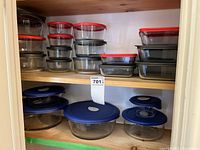 Cabinet shelves filled with stacked Pyrex glass containers and lids