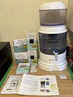 Full view of Santevia gravity filter with four replacement filter boxes, loose stones bag and manuals