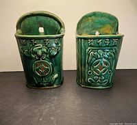 Front view of both green glazed Shiwan holders showing relief designs and characters