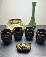 Group shot showing four bronze cups, brass vessel, green enamelled bud vase, bronze crab figure