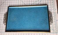 Top view of blue hammered metal tray showing bronze trim and scroll handles