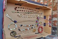 Overview of entire lot inside cardboard box showing all jewelry pieces