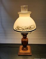 Full view of lamp lit showing shade, chimney, wood base