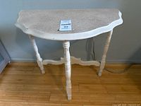 Front view of demilune side table showing distressed finish and turned legs