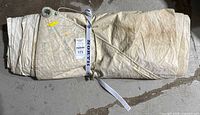 Folded off-white sail rolled and strapped with North webbing