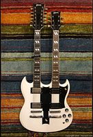 Front view of white double-neck guitar showing full body, dual necks, pickups, controls