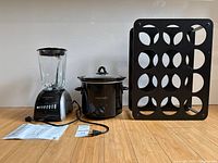 Front view of blender, slow cooker, wine rack, manuals and cords