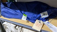 Blue sail bag on shelf with inventory tag visible