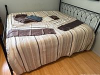 Striped comforter on bed with additional linens displayed