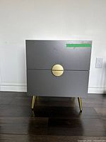 Front view of grey bedside table with brass pull and legs