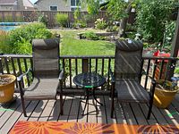 Two sling patio chairs and round side table on deck