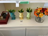 Overall lot showing urns, glass vase with flowers, red tray with spheres