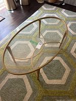 Full view of oval glass coffee table on rug