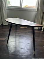 Full view of IKEA accent table showing shape, legs, and overall condition