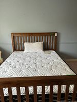 Full view of assembled wooden bed with mattress and pillow