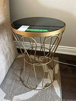 Full view of accent table beside sofa showing black glass top and gold metal frame